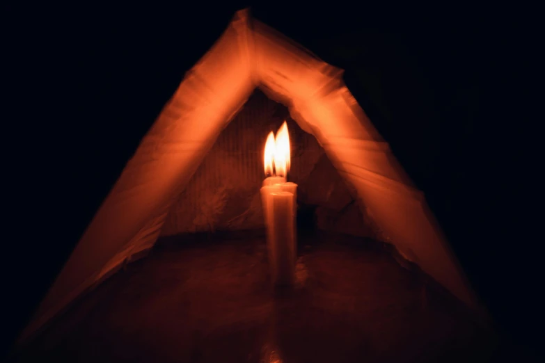 a lit candle is placed in the darkness