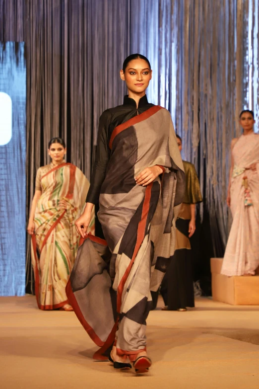a woman in sari walks down the runway