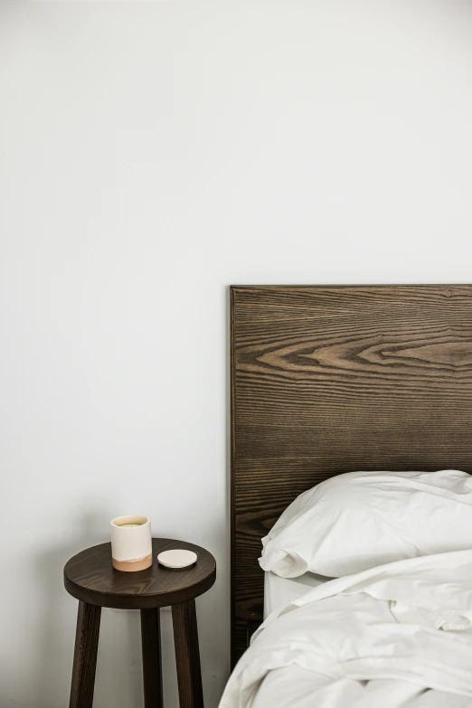 the wooden headboard of a bed with white sheets