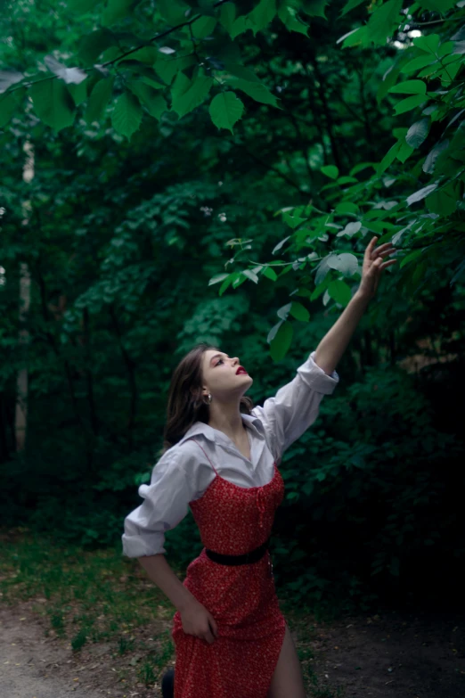 a woman dressed in red with her arms up toward the trees