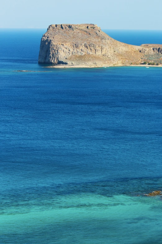 a blue body of water next to a rocky outcropping