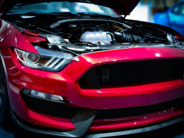 the red mustang with the hood up showing the engine