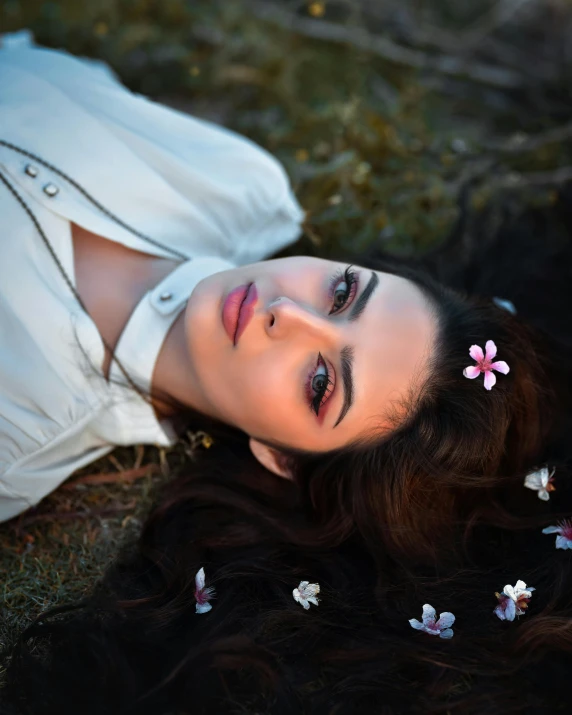 the young woman has beautiful dark eyes and is laying down