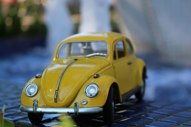 a yellow toy car is sitting on a tiled surface