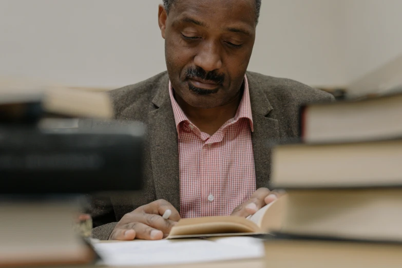 a man sits in front of several books and looks at them