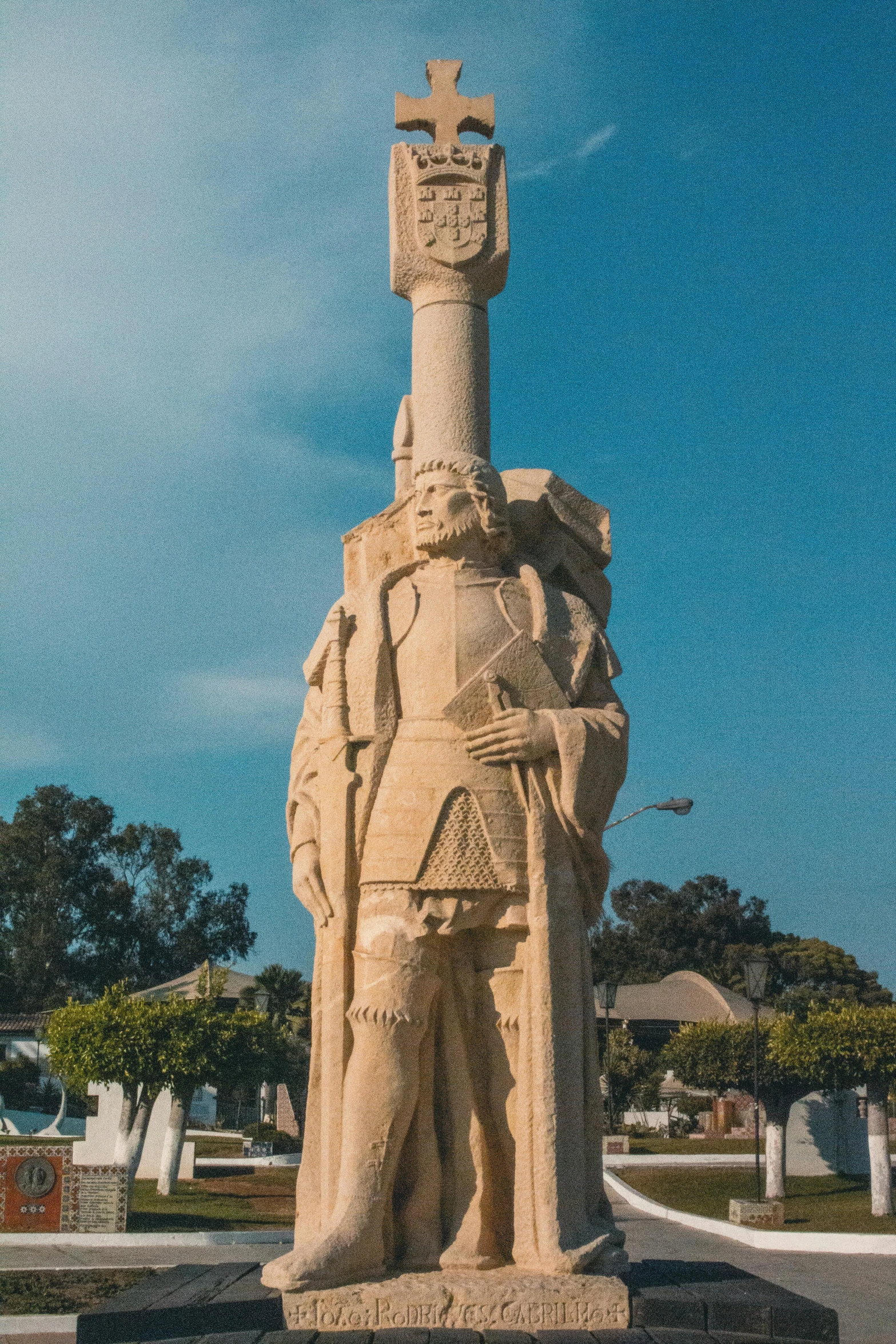 a large white statue of a person standing near a church