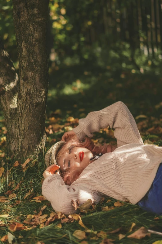 a person is laying on the ground beside a tree