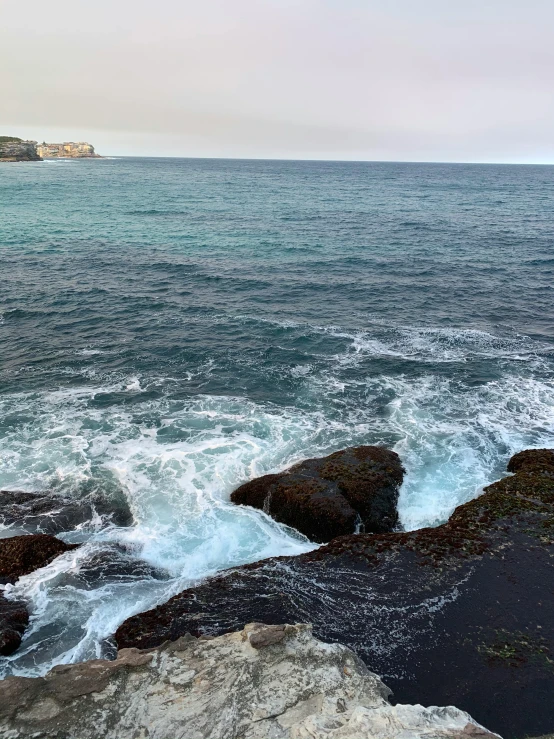 the sea is very choppy and calm by the rocky shore