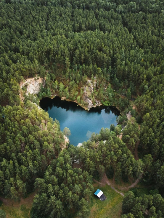 this is an aerial view of a cabin nestled in the middle of a large lake surrounded by green trees