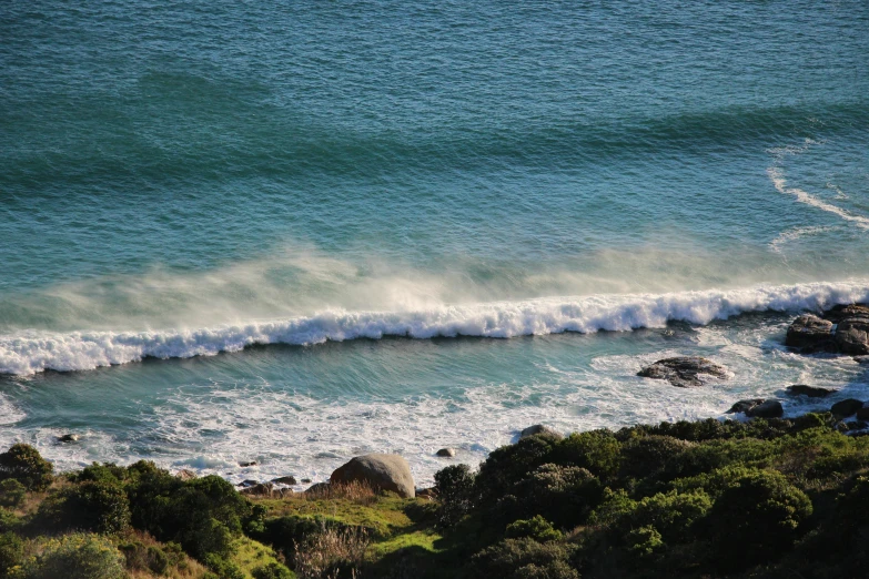 the water of the ocean is crashing onto the rocky shore