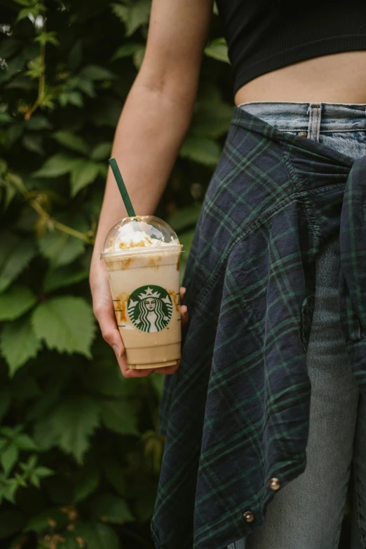 a lady's leg wearing checkered pants and carrying a cup of starbucks coffee