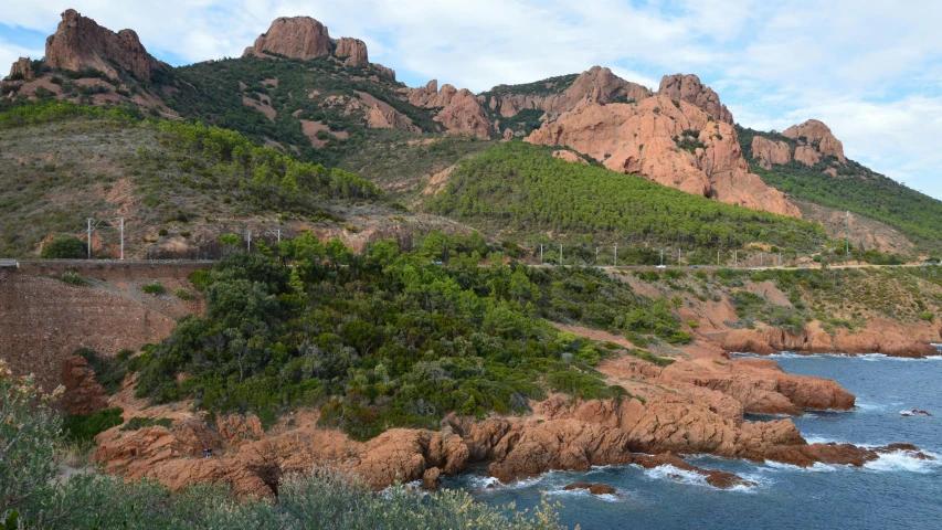 some very big rocks by the water and a hill