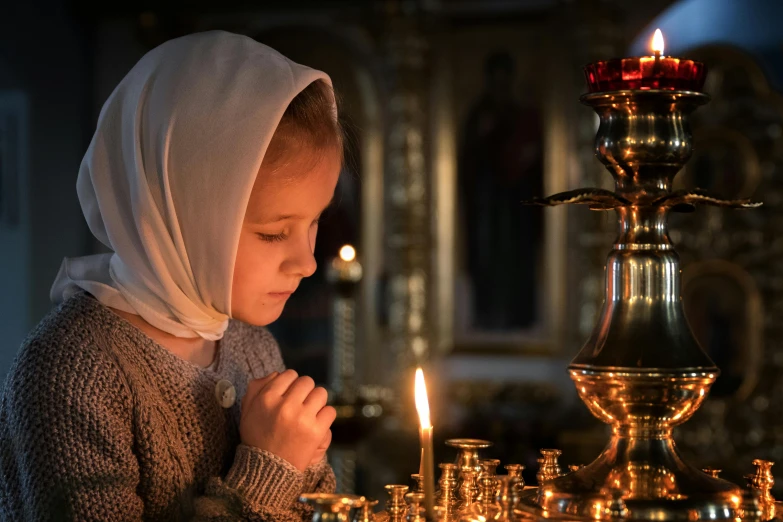 a  standing in front of a lit candle