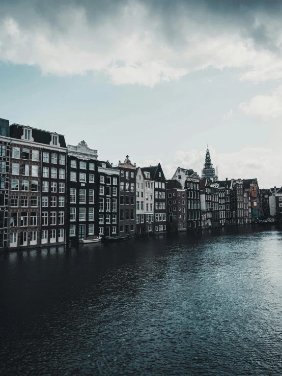 a line of building across a river on a cloudy day