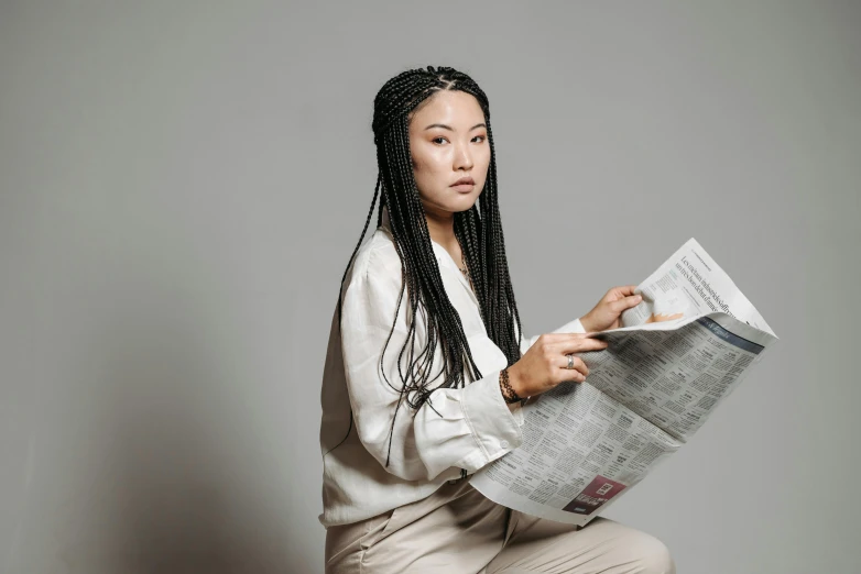 a woman in long, black ids is sitting down with a newspaper