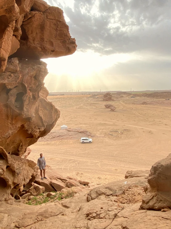 a lone man standing at the base of some rocks