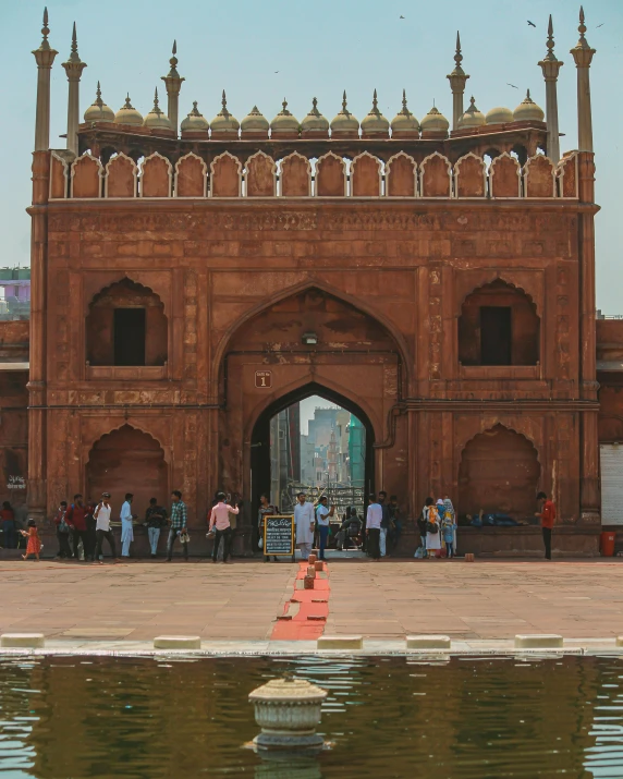 people standing outside of a brick structure by water