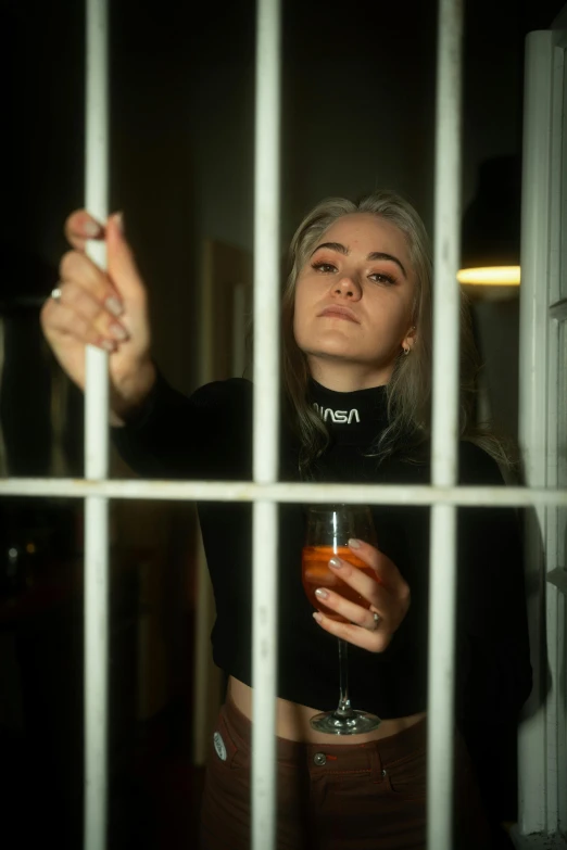 a woman standing behind bars holding up her cigarette