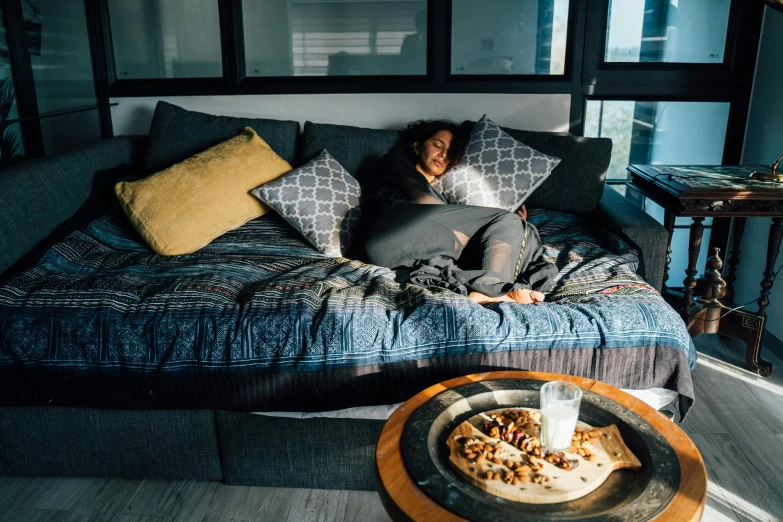 a person laying on a bed with a pizza on top