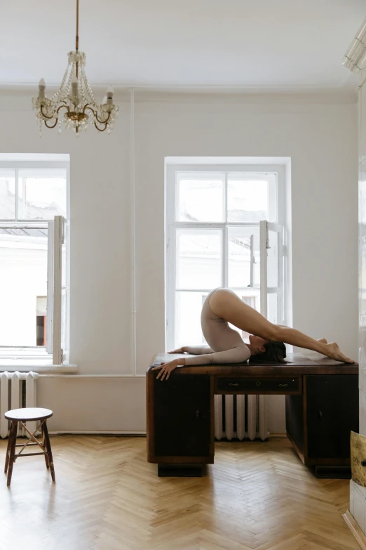 a  woman lies on a wooden desk in a room