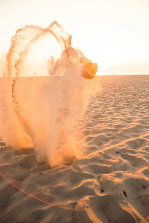 a man kicking sand at the beach on a bright day