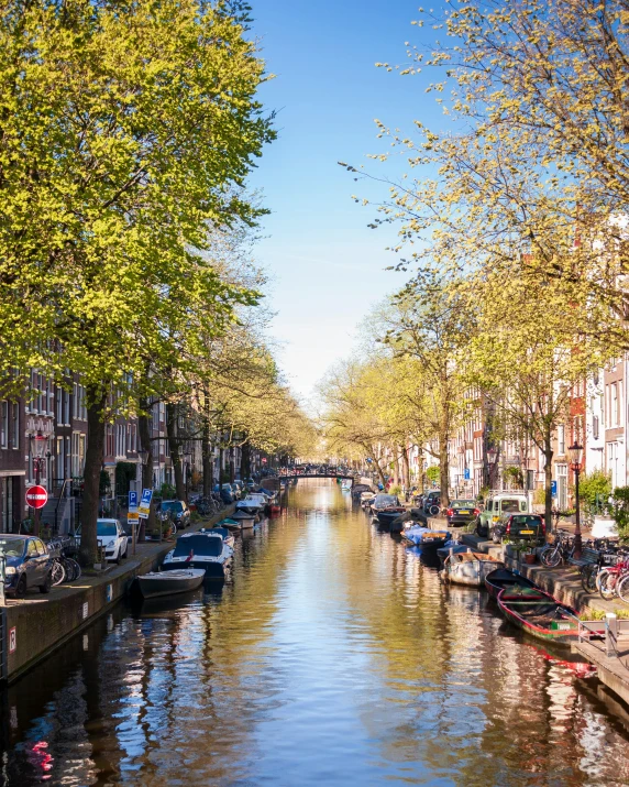 an urban canal with cars and boats parked along both sides