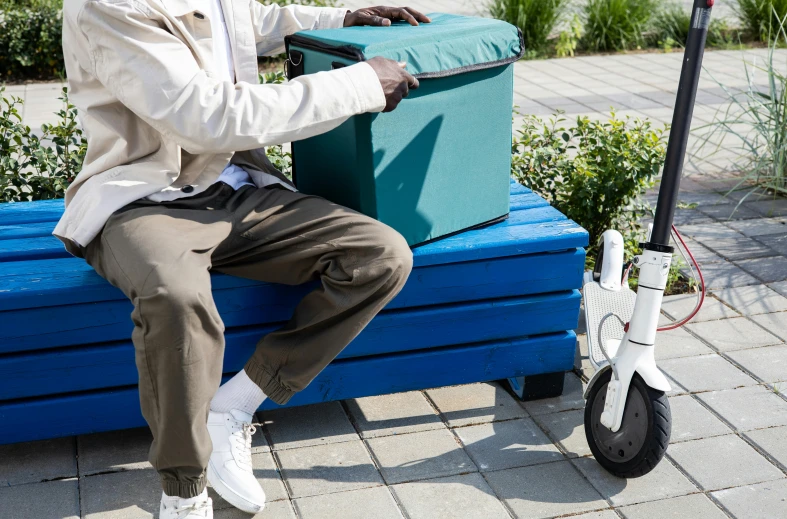 a man sits on a blue bench and holds the seat up