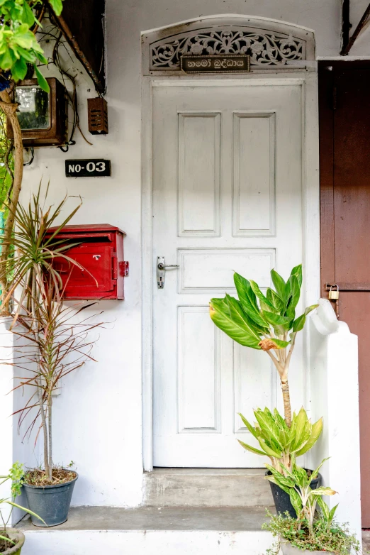 the entryway to a home with a mail box and potted plants