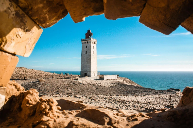 looking into the distance of a light house, with blue water in the background