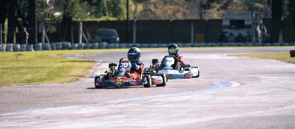 three people on three wheeled race cars going around a curve