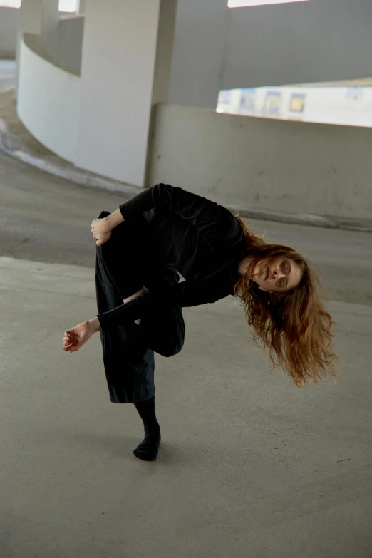 a woman with long hair, leaning up against a building