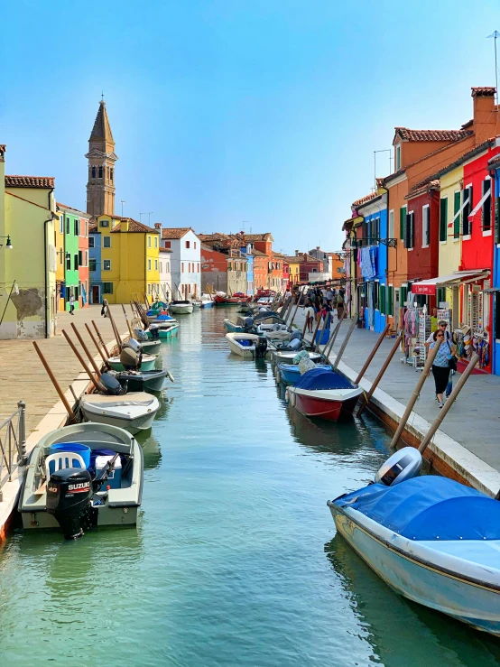 several boats are parked along a row of water lined up in front of buildings