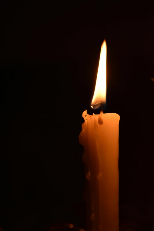 a lit candle in the dark with one of it burning