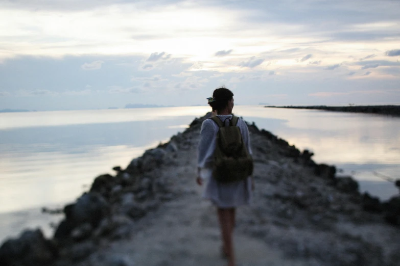 a woman standing by a body of water with her back to the camera