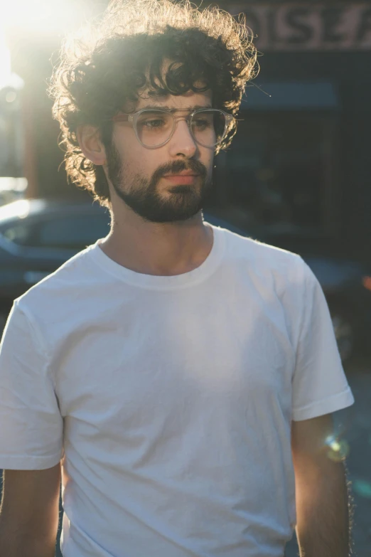 a man with glasses standing on a sidewalk