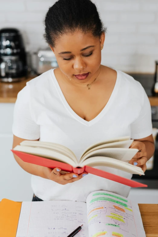 a woman is reading and studying books with a pen in front of her