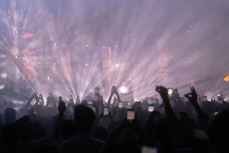 several people holding their cell phones in front of fireworks