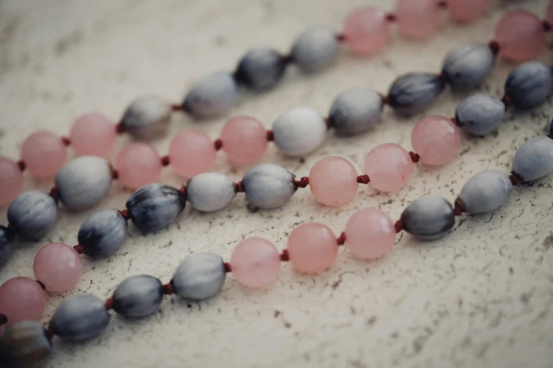 a very long bead necklace with some pink and grey beads