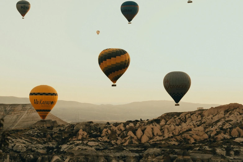 multiple  air balloons in the sky above a mountain range