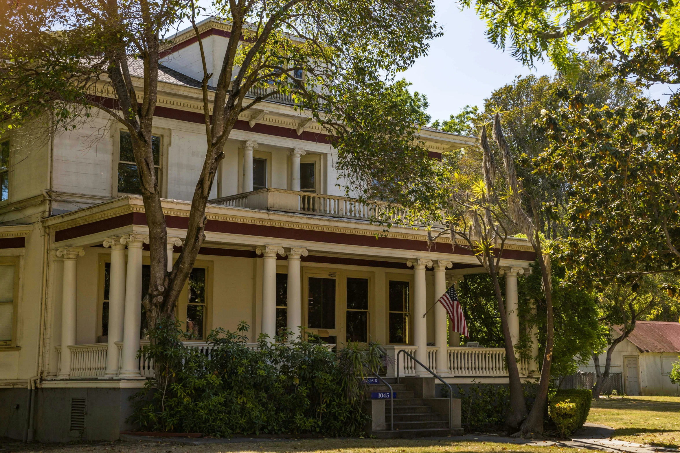 a very old two story white house with an american flag