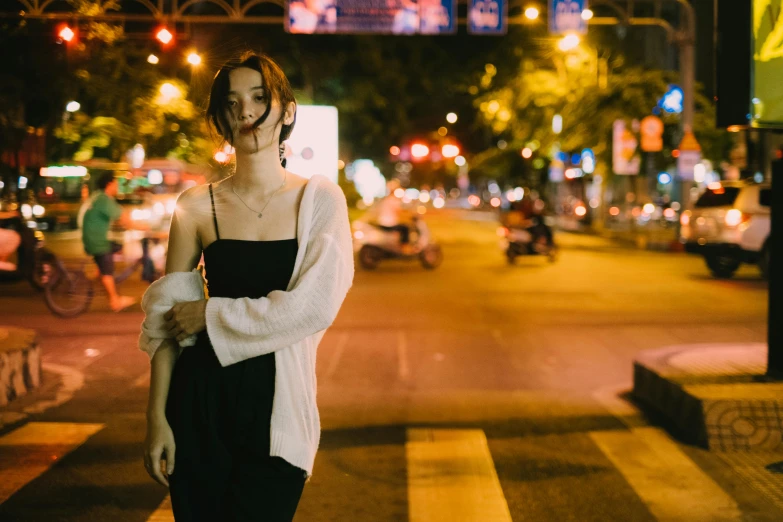 woman with shoulder pads walking down a street at night