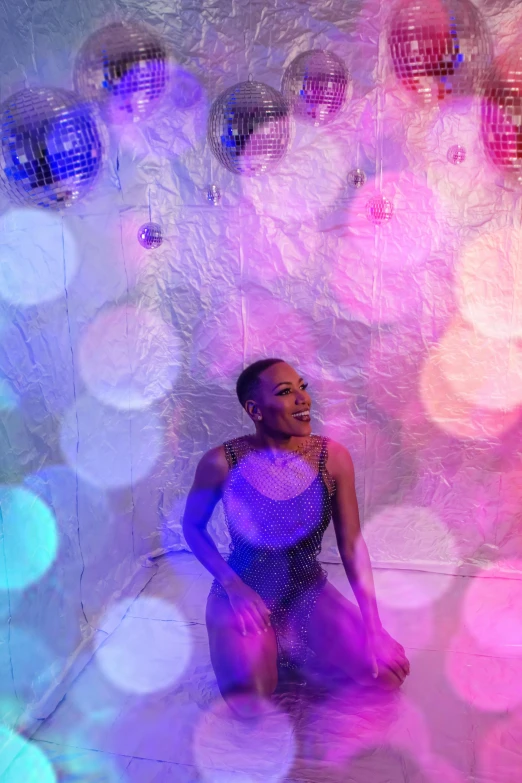 a  with a purple and blue disco dress sitting in front of colorful bubbles