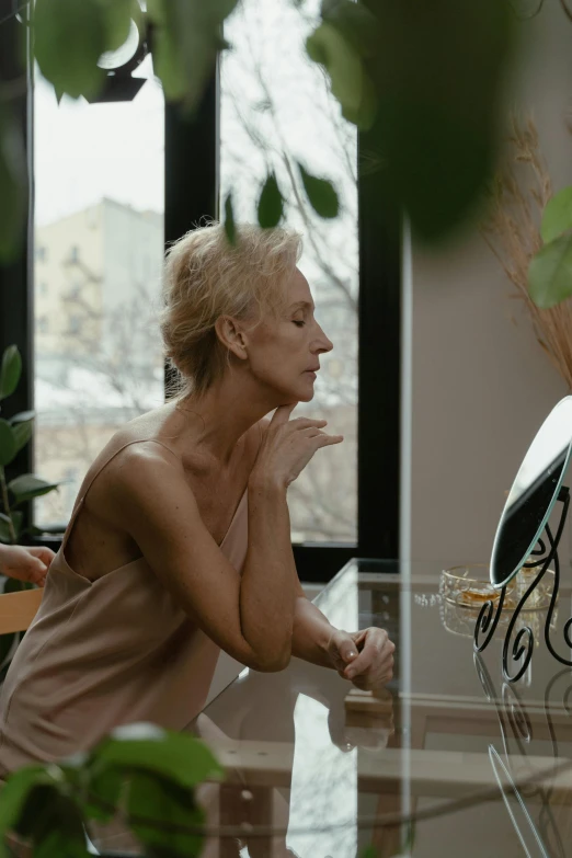 an old woman sitting at the table in front of a wine glass