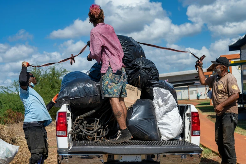 men are unloading bags onto the back of a truck