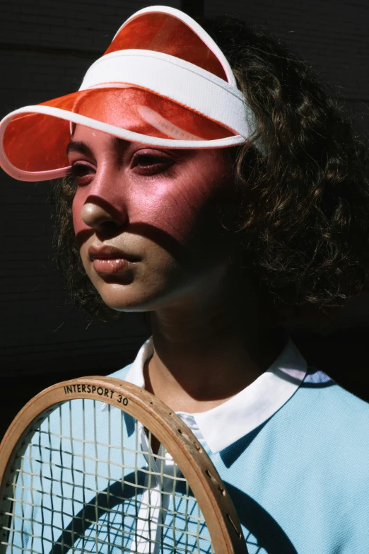 the girl in a white and red hat is holding a tennis racket