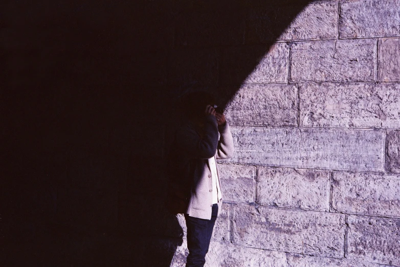 woman in white shirt leaning against a wall