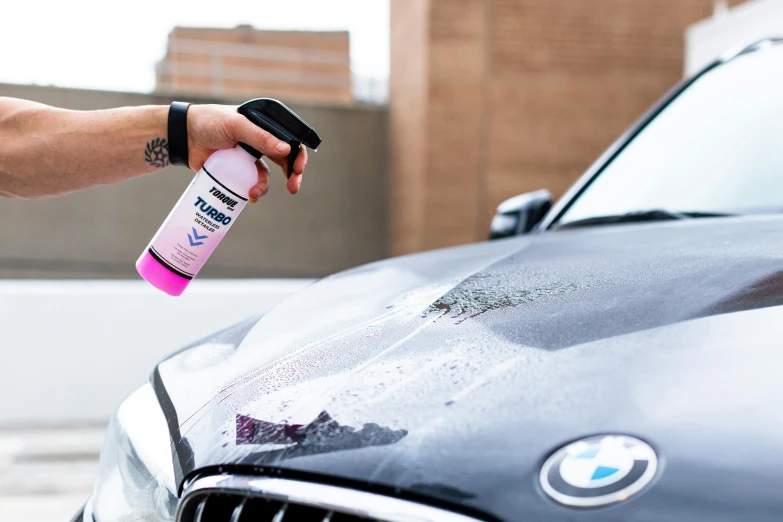 someone spray - washes the bmw car with a pink aerosol