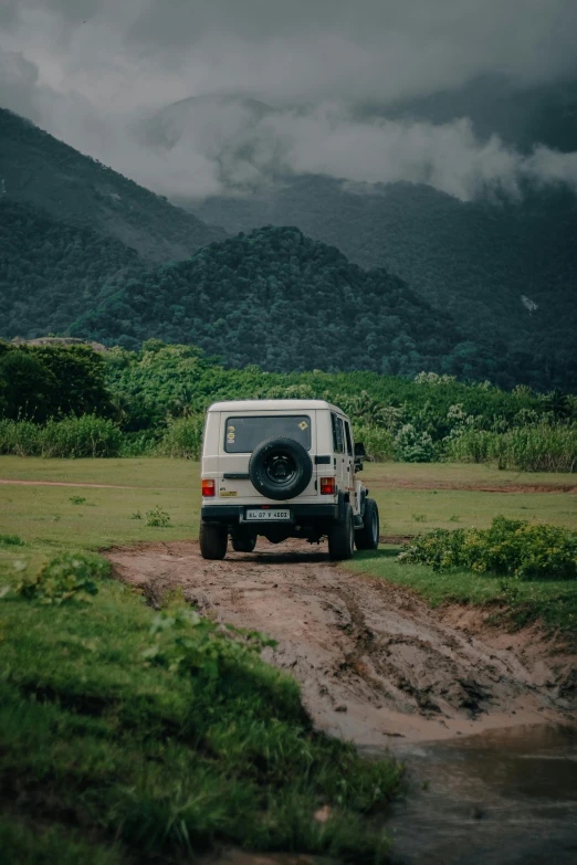 a jeep sits on a dirt road in the middle of a field