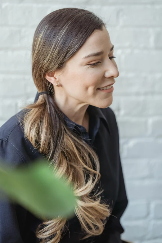 a woman sitting in front of a white brick wall