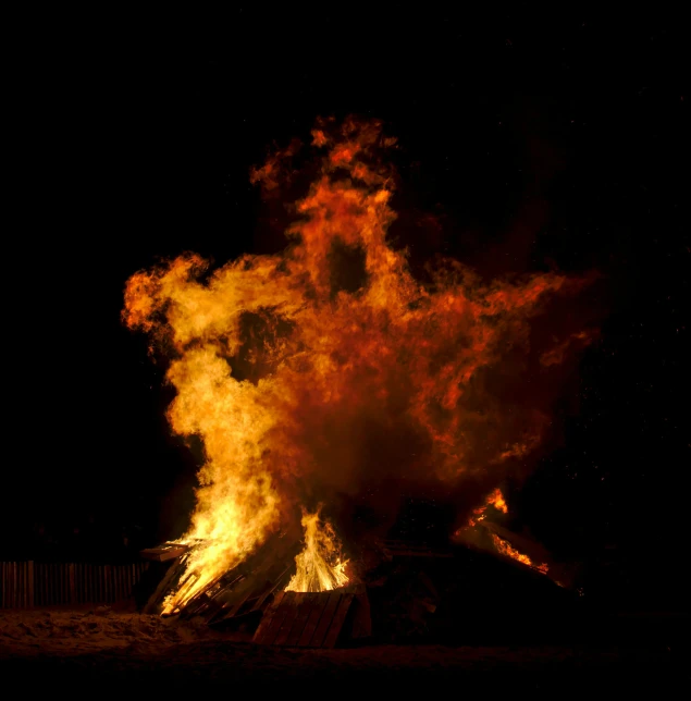 a dark sky with flames rising from it and a building on fire